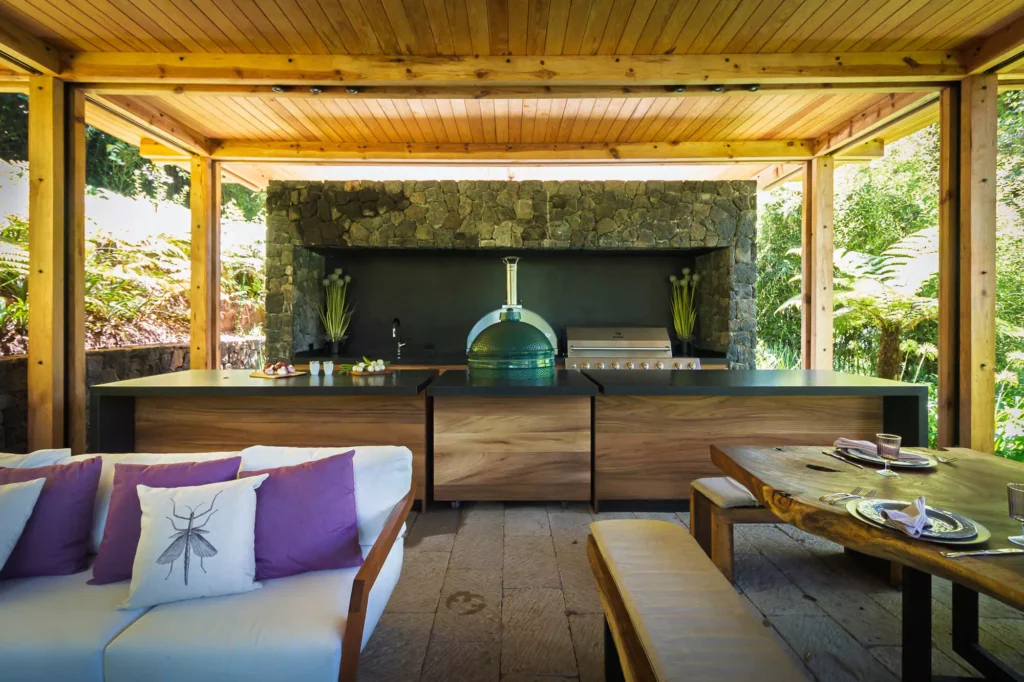 Wood and stone outdoor kitchen surrounded by greenery, designed by Vitelier at Club de Golf Avándaro, State of Mexico.