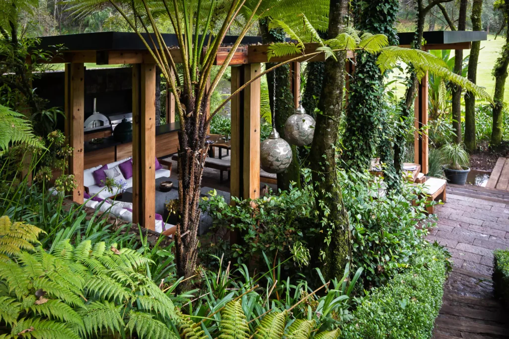 Wood and stone outdoor kitchen surrounded by greenery, designed by Vitelier at Club de Golf Avándaro, State of Mexico.