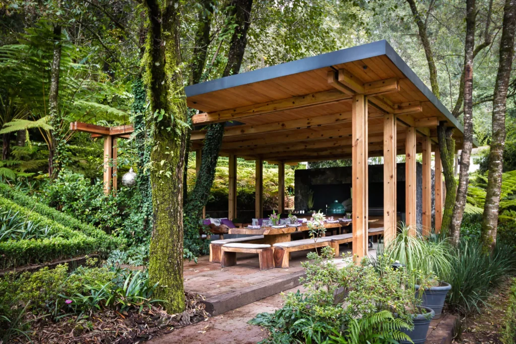 Wood and stone outdoor kitchen surrounded by greenery, designed by Vitelier at Club de Golf Avándaro, State of Mexico.