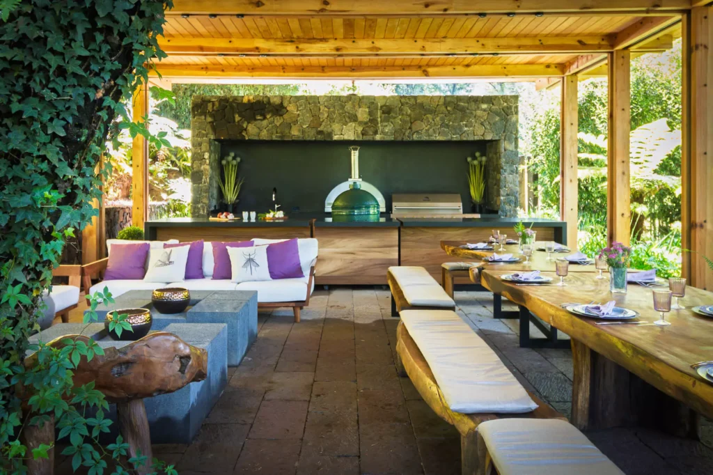 Wood and stone outdoor kitchen surrounded by greenery, designed by Vitelier at Club de Golf Avándaro, State of Mexico.