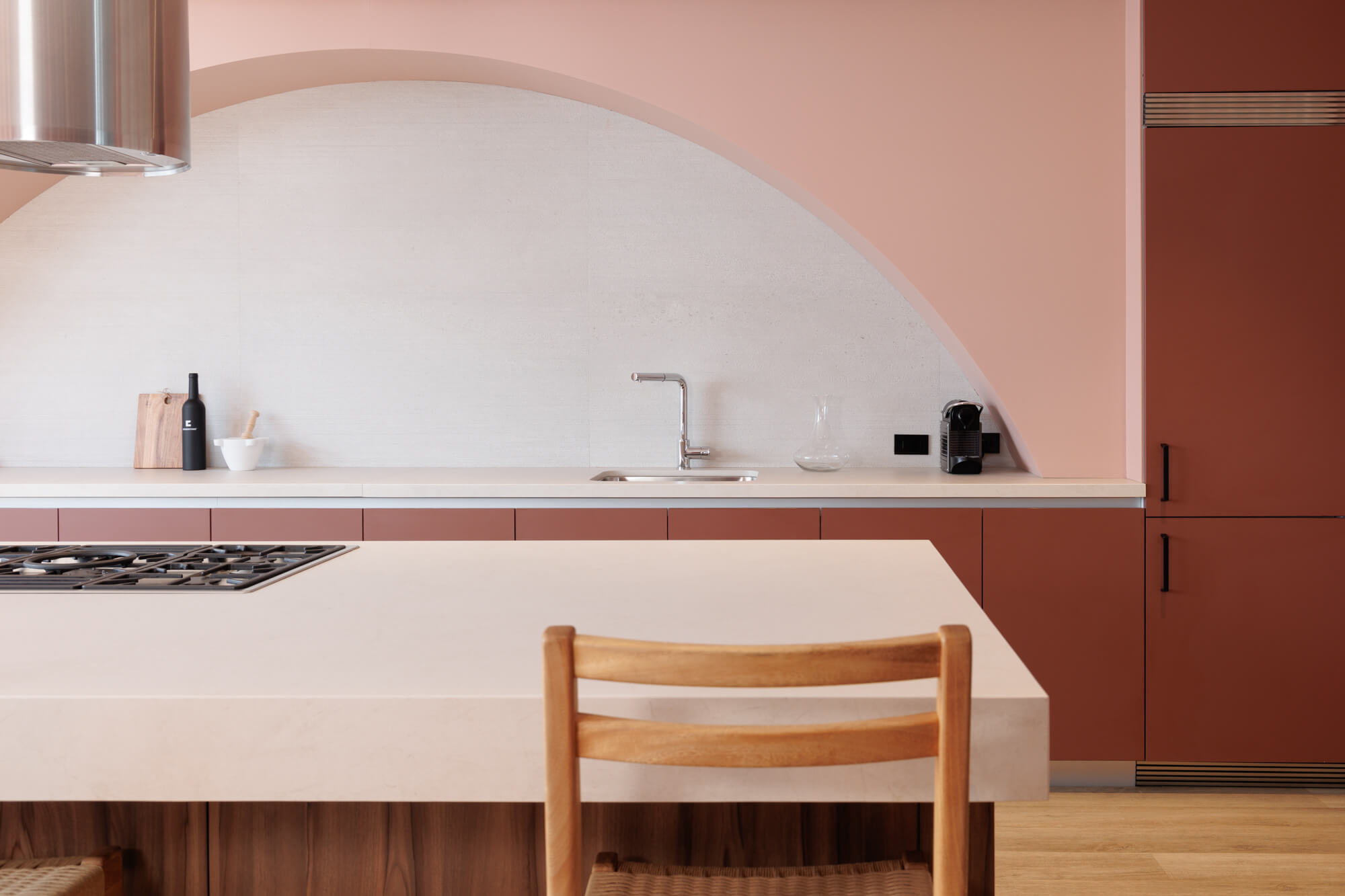 Cocina rosa con isla, arco y campana