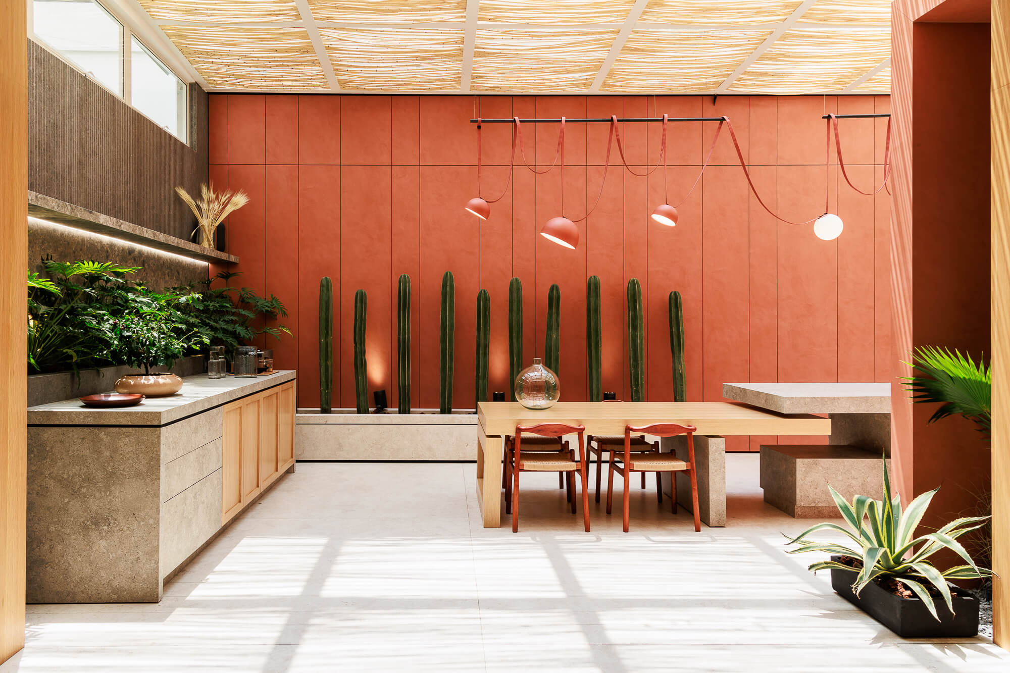 Cocina roja en tono terracota con isla central y plantas decorativas