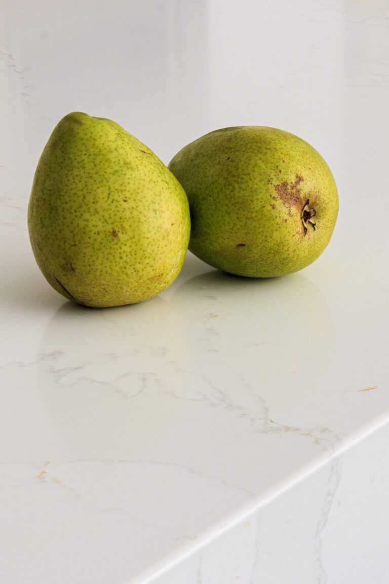 Dos peras sobre una cubierta de cocina blanca elaborada en cuarzo Silestone de Cosentino, simulando la apariencia del mármol para cocina.