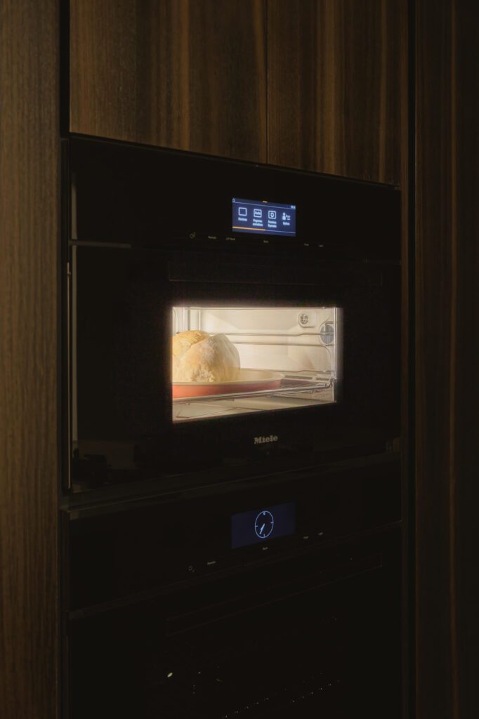 Hogaza de pan recién horneándose en el horno de vapor de Miele, con la puerta cerrada y la luz encendida.