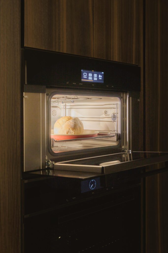 Hogaza de pan recién horneada en el horno de vapor de Miele, con la puerta abierta y la luz encendida.