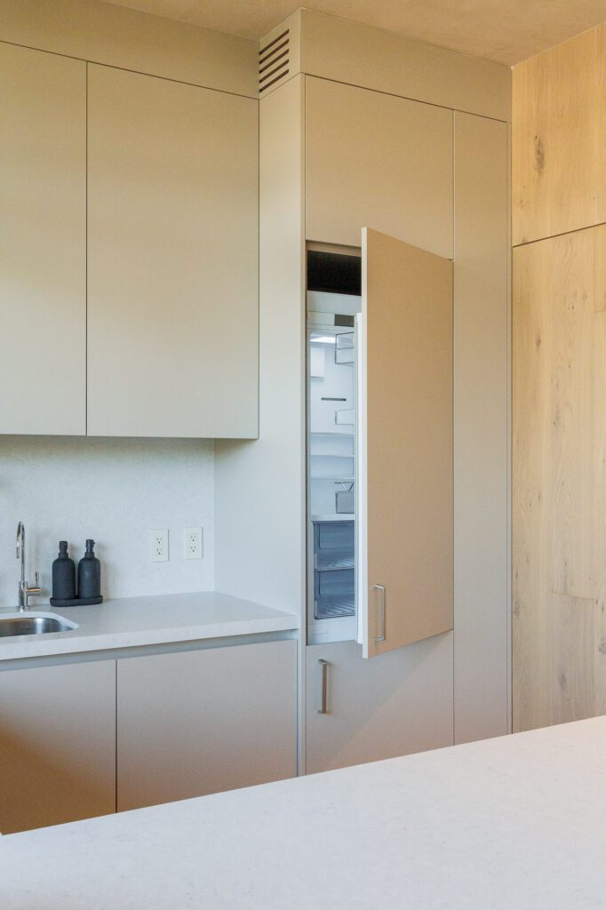 Refrigerador panelable, con la puerta abierta, en una cocina minimalista color beige.