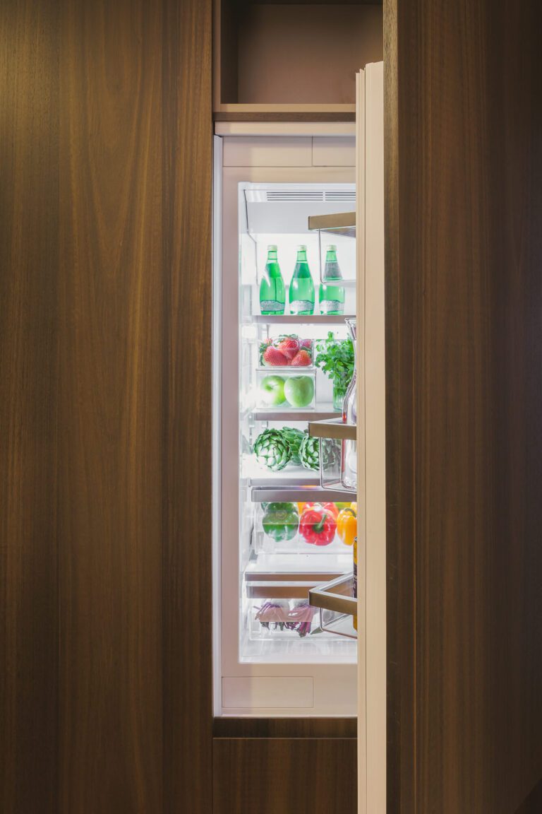Refrigerador panelable, con la puerta abierta, en una cocina de madera.