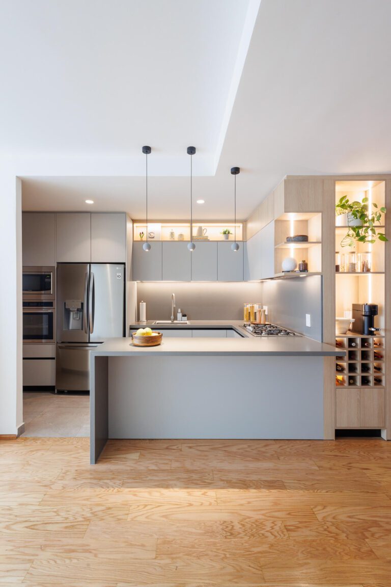 Cocina abierta al comedor con barra en color gris claro.