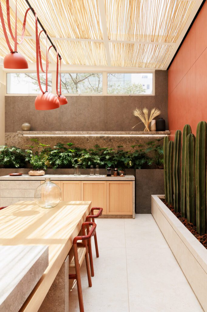 Diseño de cocina moderna con superficies de piedra y madera clara, y vegetación integrada