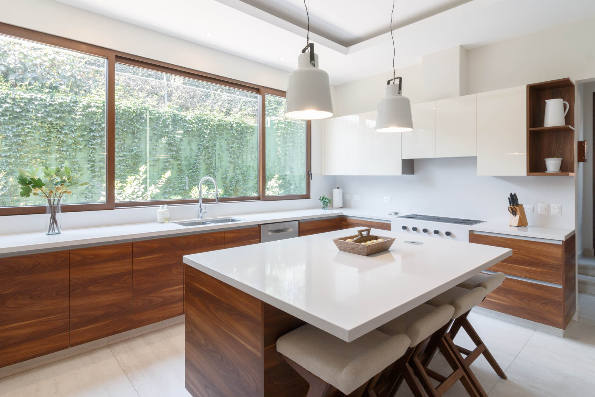 Cocina con isla central, muebles de madera y ventana grande.
