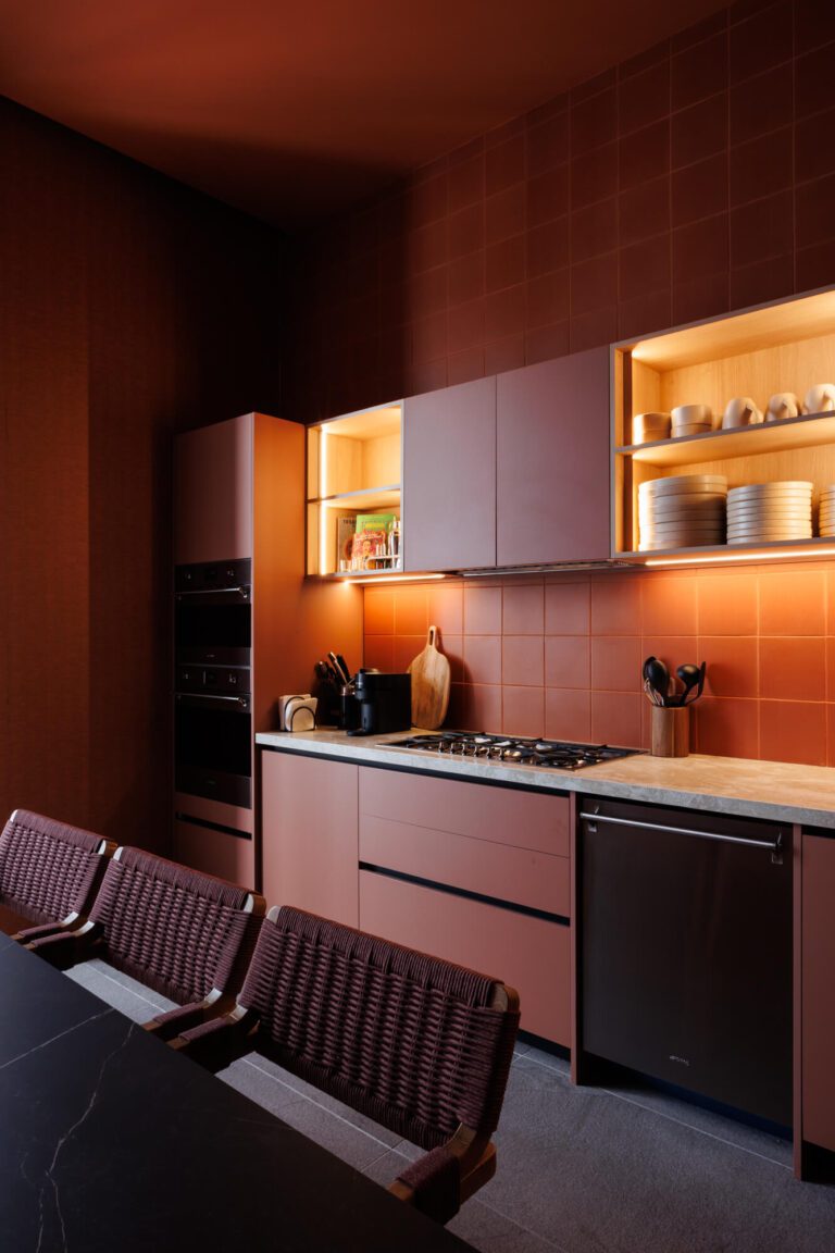 Cocina roja burdeos monocromática con azulejos, mesa de comedor negra y nichos iluminados