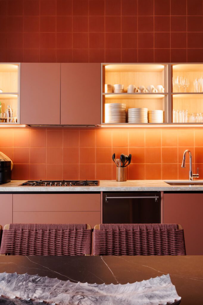Cocina roja burdeos monocromática con azulejos, mesa de comedor negra y nichos iluminados