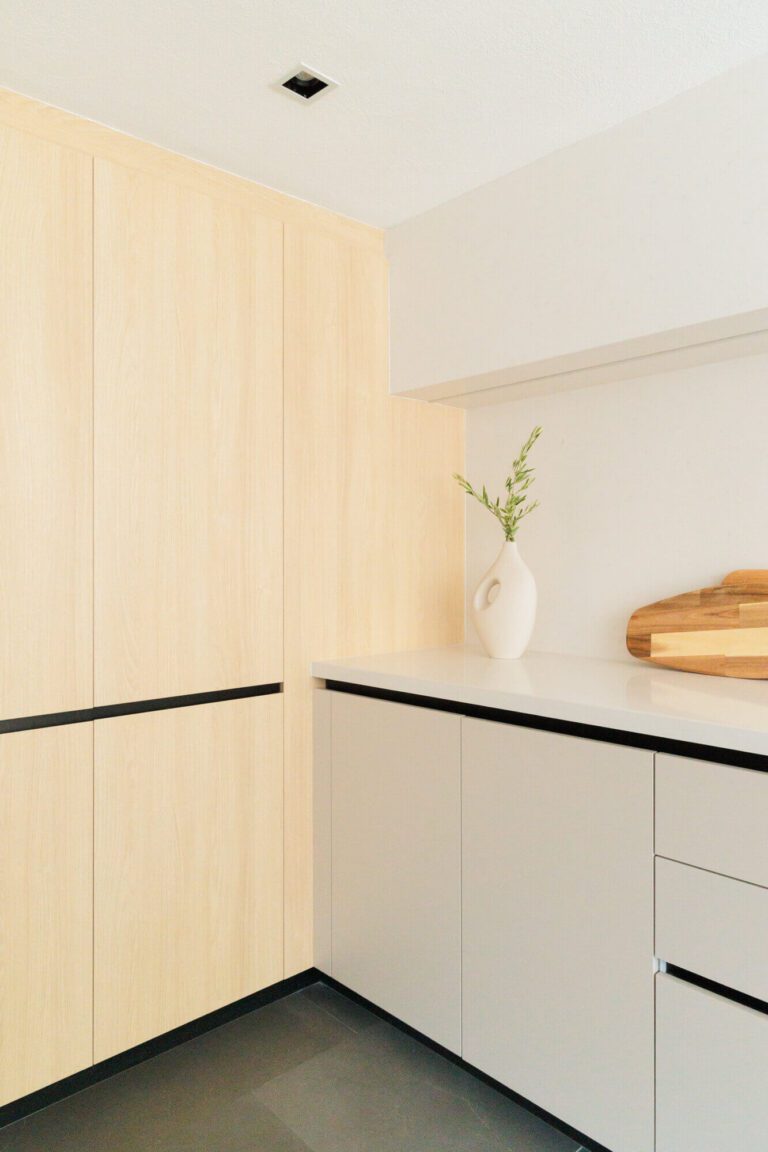 Esquina de una cocina minimalista en color beige con muebles de madera clara