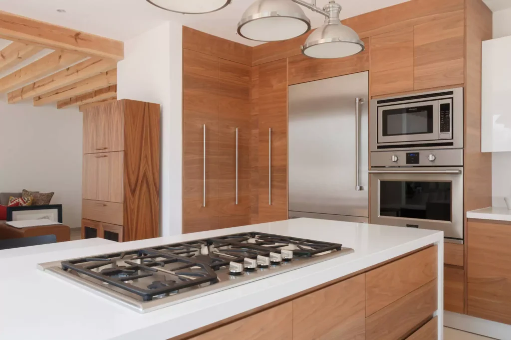 Cocina funcional de madera con isla central y torre de hornos