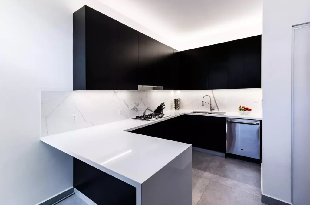 Pequeña cocina blanca y negra con península, parrilla y gabinetes flotantes