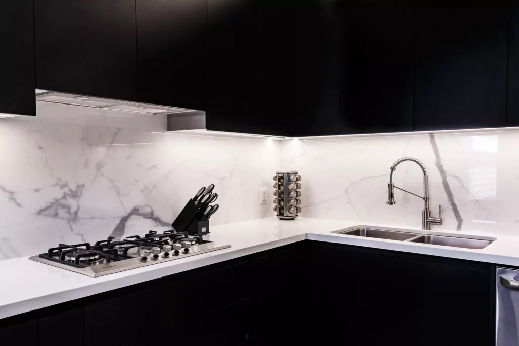 Cocina blanca y negra con salpicadero con vetas, parrilla y gabinetes flotantes