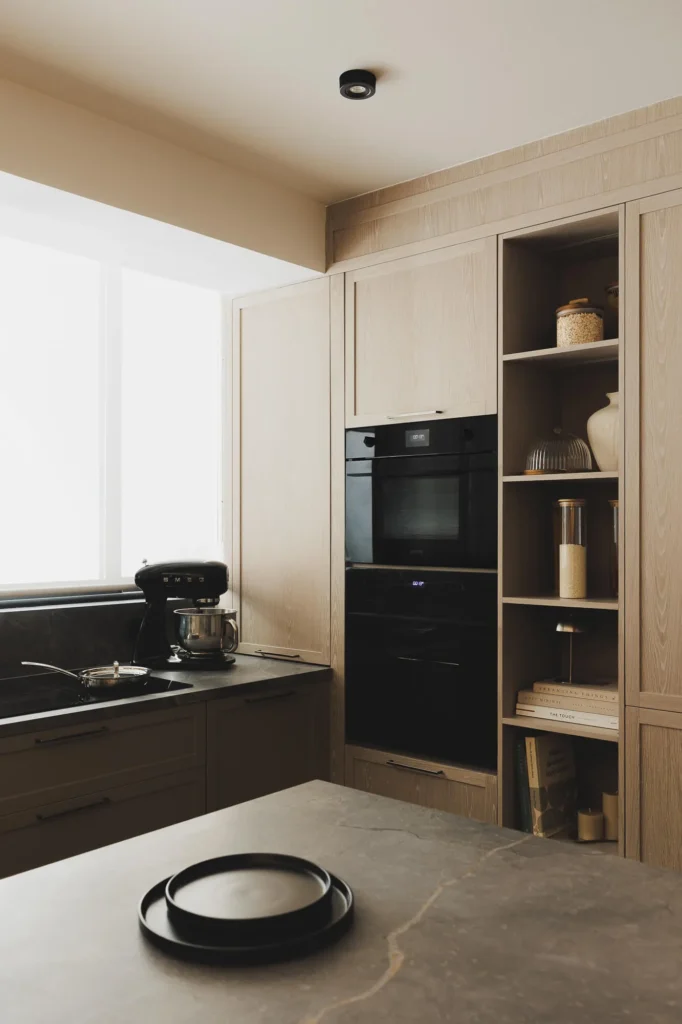Oven tower, open module, and panel-ready appliances in a patina wood kitchen with sintered stone countertop