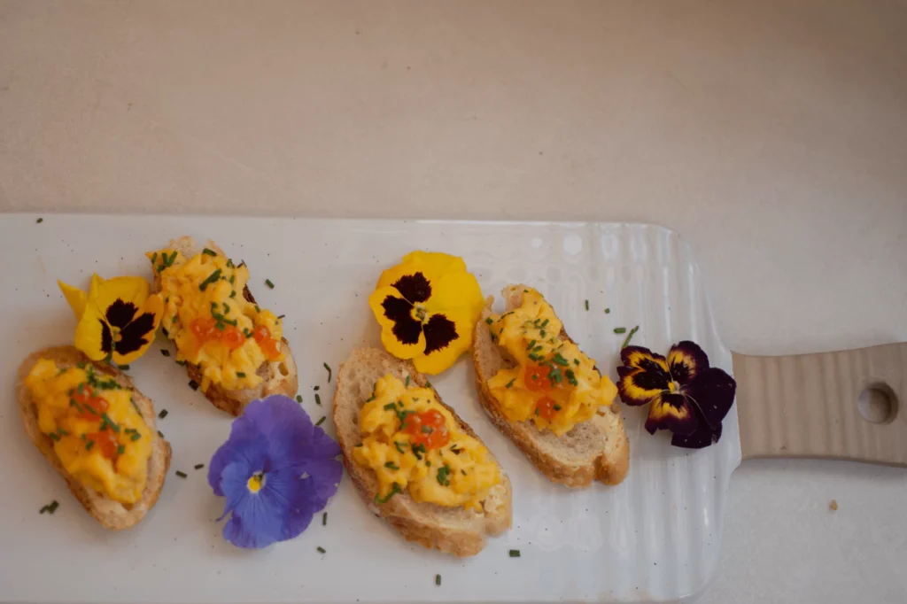 Montaditos con flores comestibles, servidos sobre una tabla de Zash