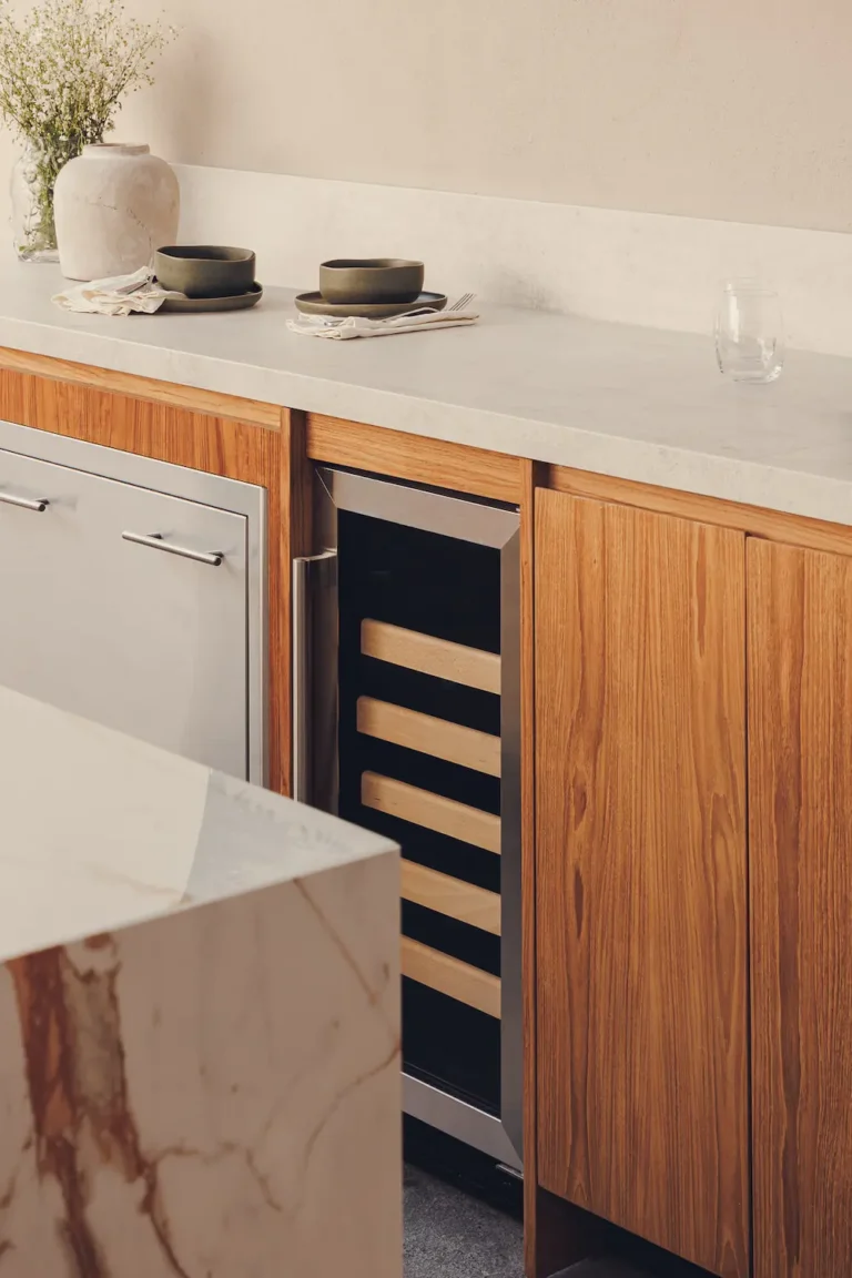 Detalle de mueble de cocina con frentes de madera y cubierta de piedra sinterizada e isla dekton.