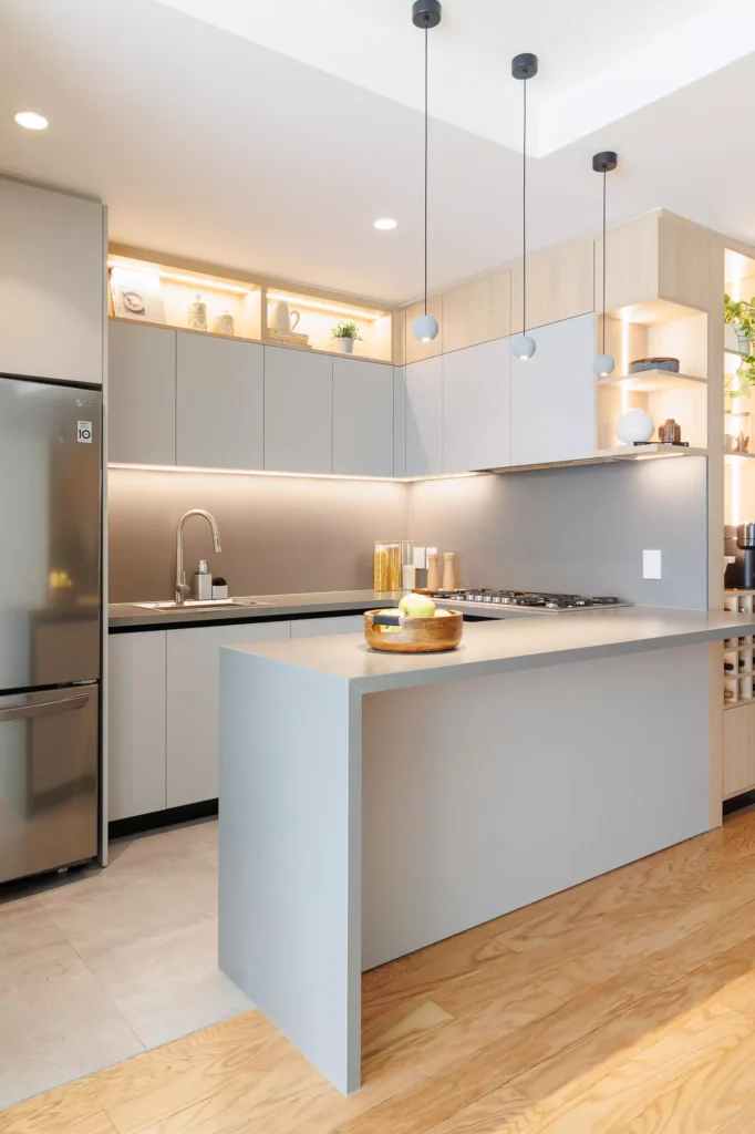 Kitchen with peninsula showing integrated cooking appliances and grey lacquered cabinetry designed by Vitelier