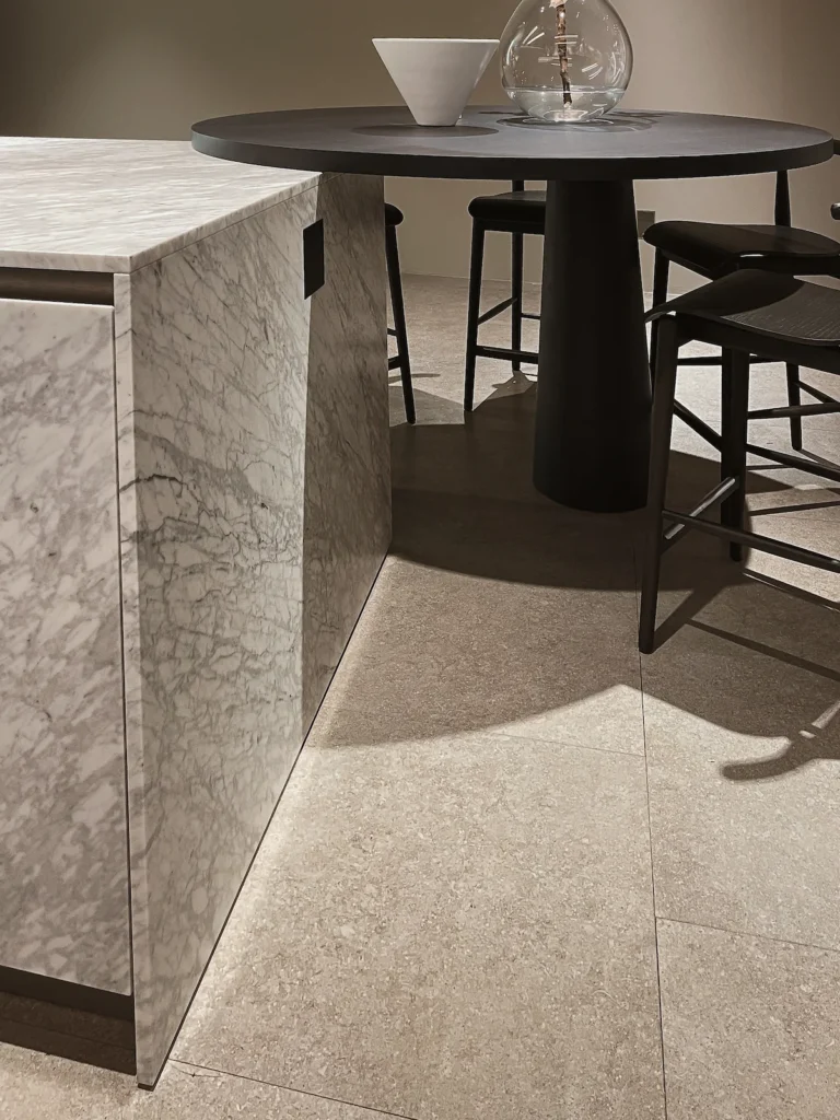 Mesa ovalada integrada a isla de cocina con base curva en EuroCucina 2026 Milán