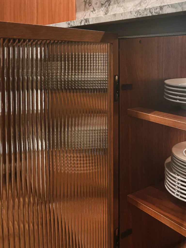 Vitrina con puerta de cristal acanalado y estantería interior de madera en EuroCucina 2026.