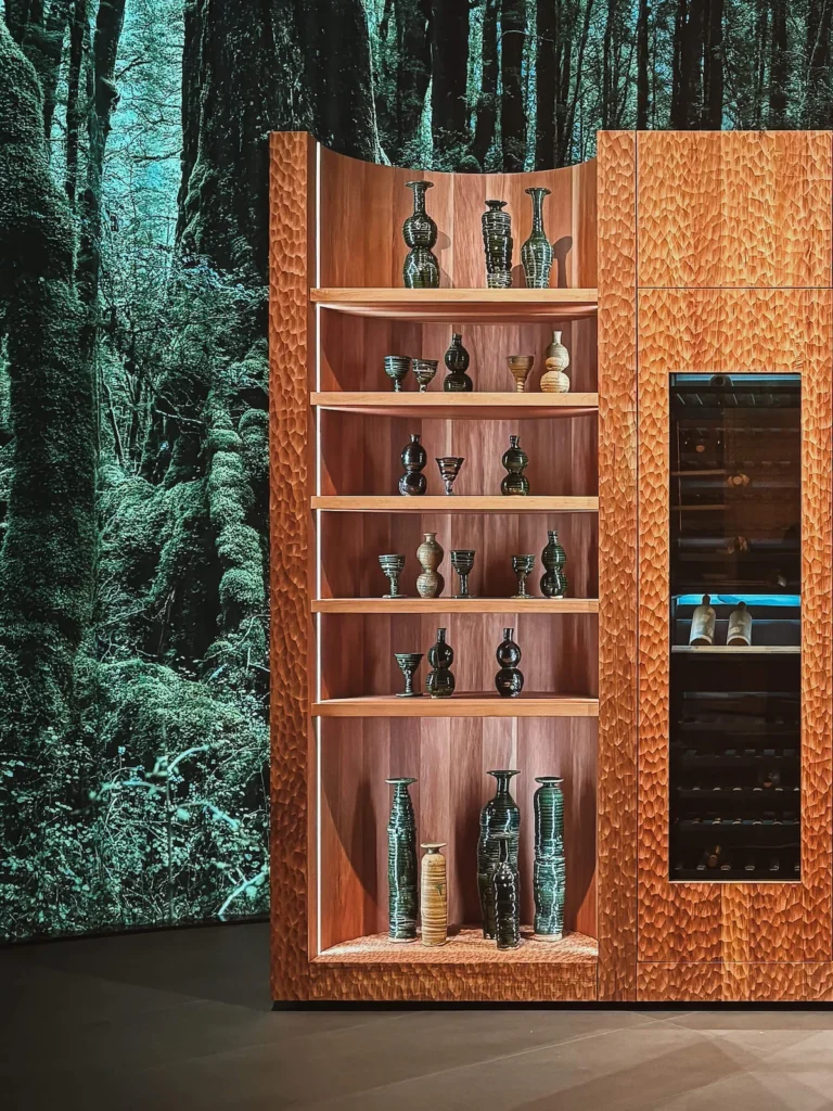 Vitrinas de madera tallada en tono ámbar con luz cálida interior en el stand Fisher & Paykel Nature-Ritual.