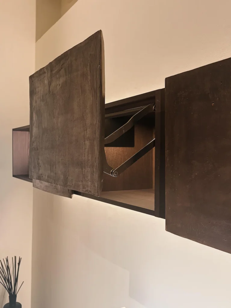Módulo alto colgado de Minotti Cucine, colección Terra en terracotta (Claudio Silvestrin), con puerta abatible en placa de terracotta de canto irregular e interior en madera clara, EuroCucina 2026.