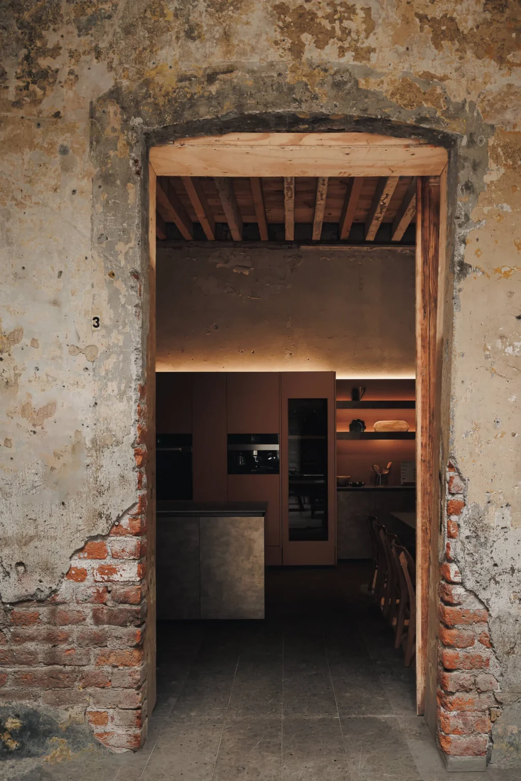 Access to the Casa Taittinger kitchen from an exposed-brick doorway of Proyecto Público Prim — design by Vitelier over 1905 Porfirian architecture, Mexico City.