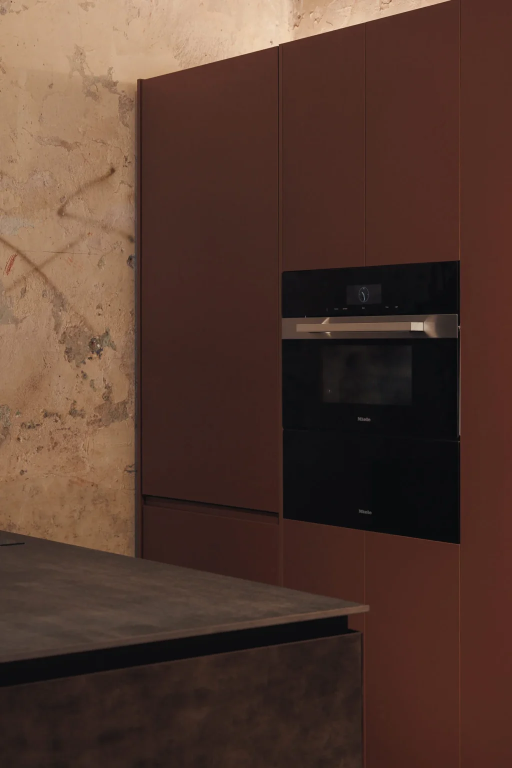 Miele compact combi-steam oven integrated into the Interforest copper laminate wall, over the patinated walls of Proyecto Público Prim.