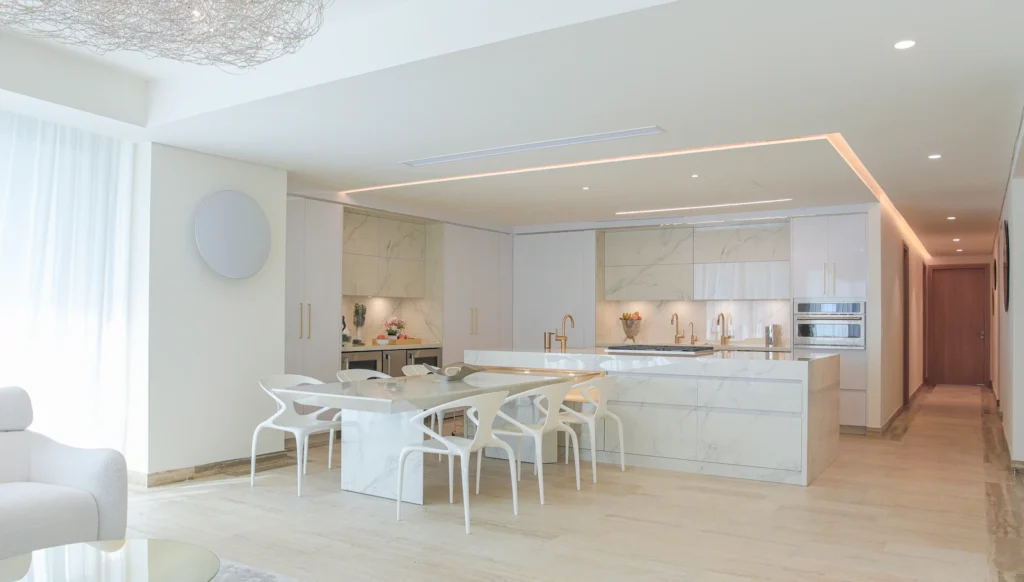Mesa móvil en Dekton Natura adosada a la isla central con comedor integrado y cocina abierta en departamento de Acapulco.