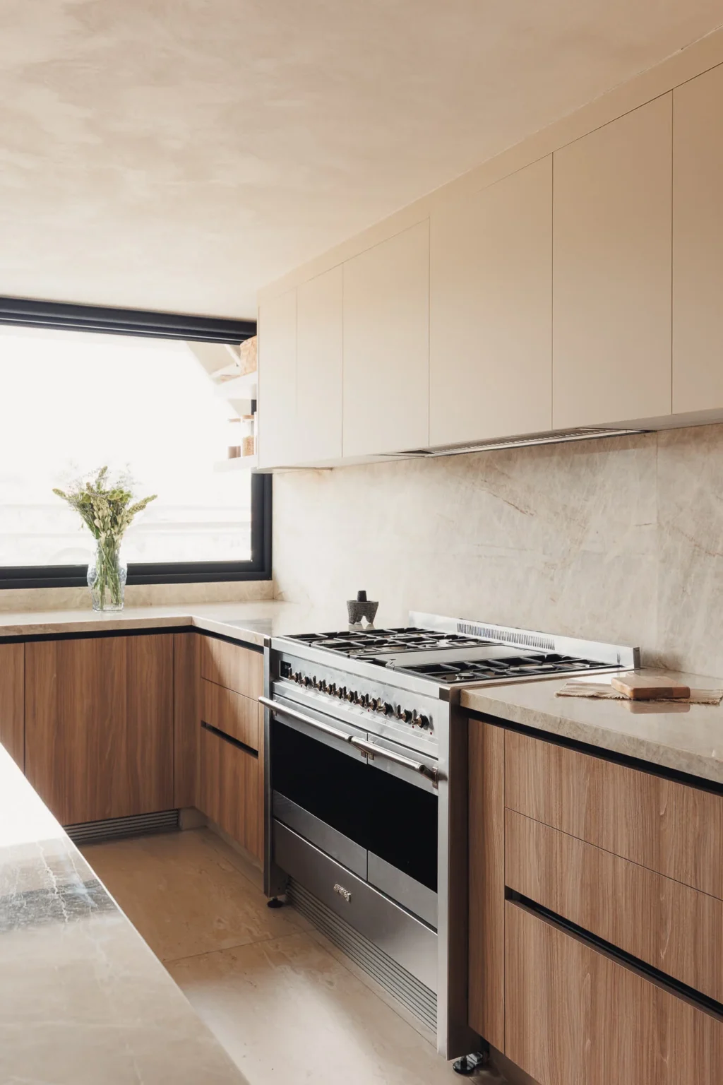 Estufa Smeg de formato profesional con cubiertas de cuarcita Taj Mahal y gabinetes Maple Samsara junto a ventanal con flores — cocina residencial en CDMX por Vitelier.