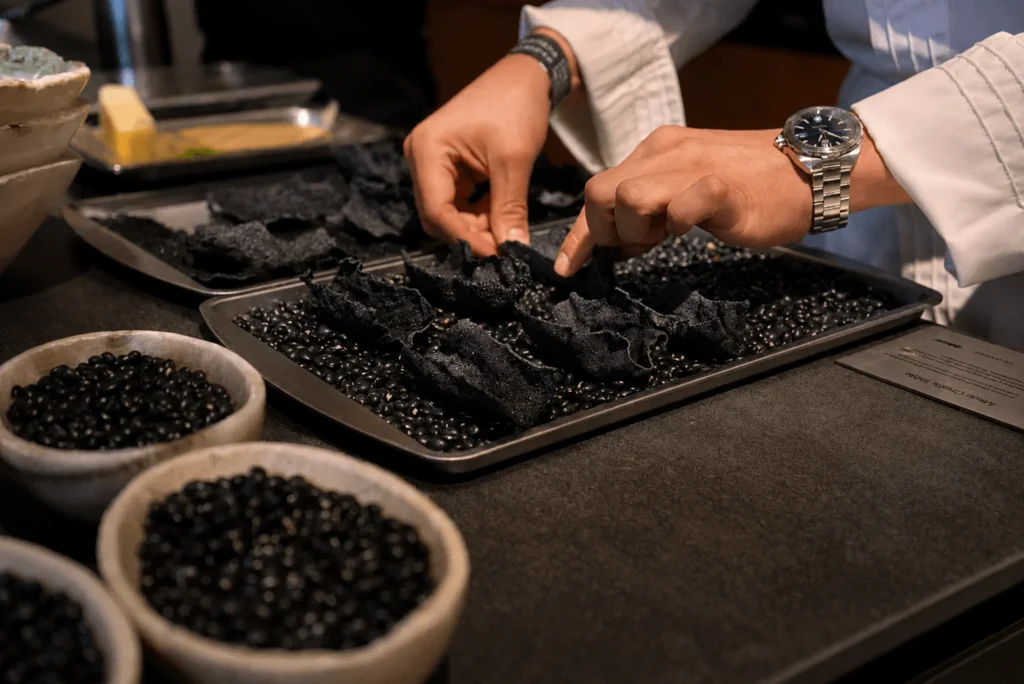 Manos de chef preparando crujientes de frijol negro durante Miele Chef's Table en Casa Taittinger